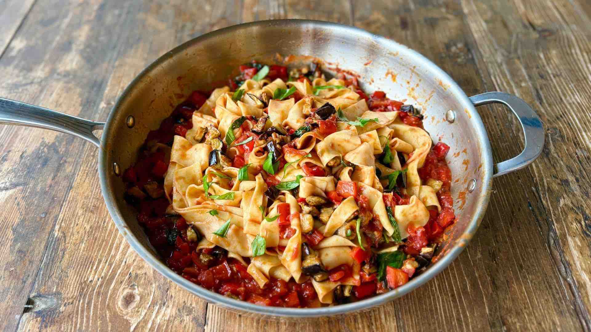 Pan of handmade pappardelle pasta tossed in roasted vegetable and tomato sauce